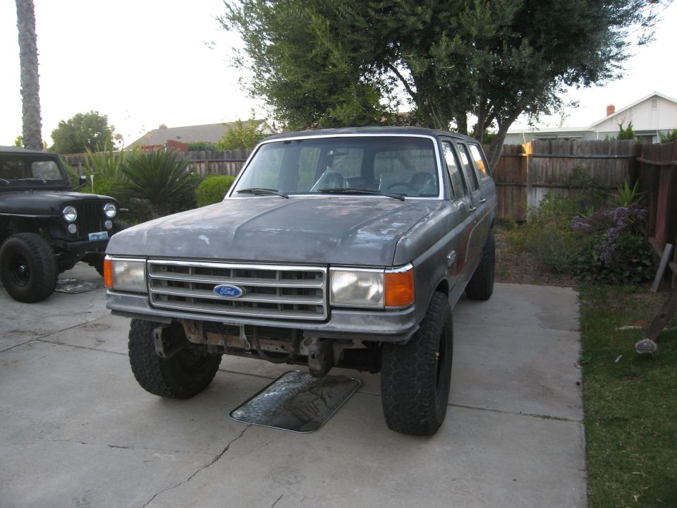 Gray Ford Bronco parked next to a black Jeep. Bronco has a silver grille and is lifted