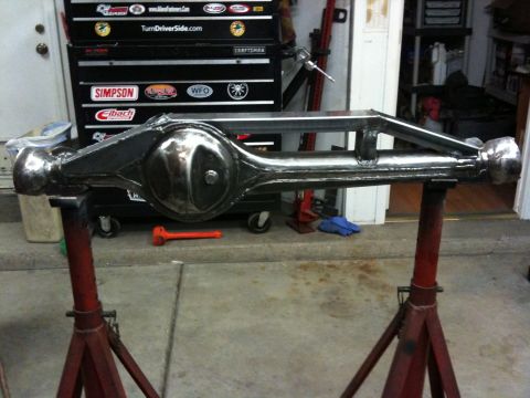 Suzuki Samurai - A custom chrome front axle assembly is displayed on red stands in a garage setting.