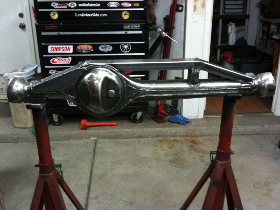 Chrome front axle assembly on red stands, with a toolbox in the background