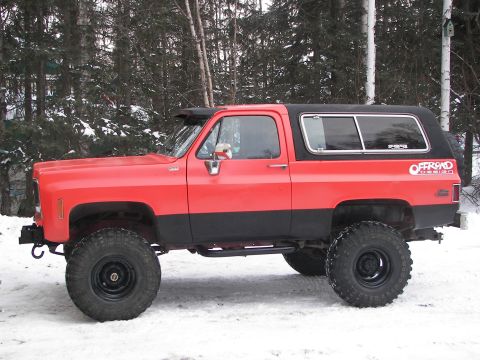 1990 Chevrolet Suburban - This lifted SUV, likely from the 1980s, is shown in a snowy, wooded environment.