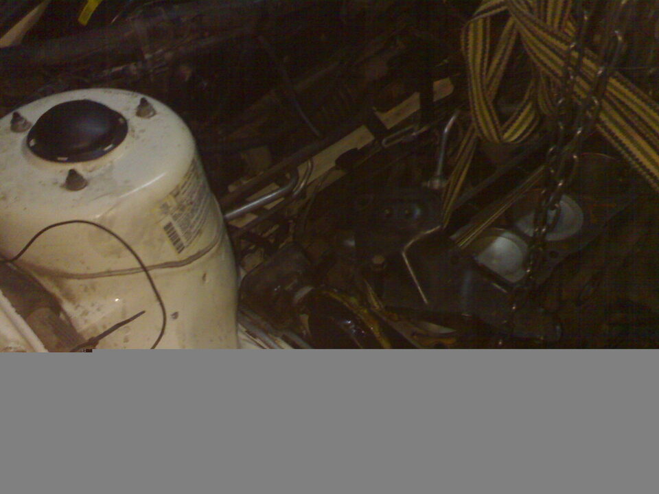 White engine component with black cap and wires, surrounded by engine parts and wiring