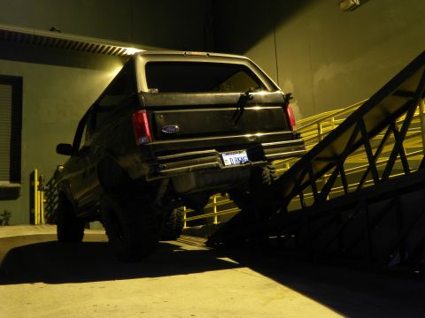 1995 Ford Bronco - 1995 Ford Bronco rear view, partially on a metal ramp at night.