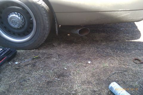2000 Mercury Grand Marquis - The rear wheel and exhaust pipe of a 2000 Mercury Grand Marquis are visible, with a Mercury badge on the hubcap.