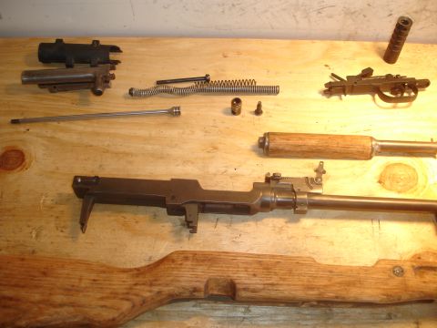 1989 Ford Bronco - Various components of a firearm are disassembled and arranged on a wooden workbench.