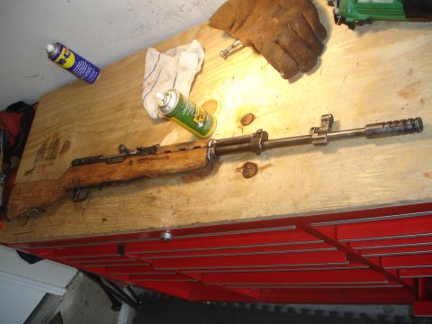 1989 Ford Bronco - A rifle is laid out on a wooden surface next to cleaning spray and a work glove.