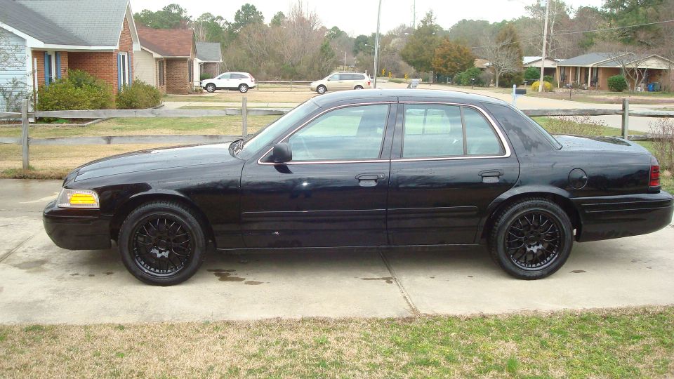 black sedan parked in a driveway, aftermarket wheels