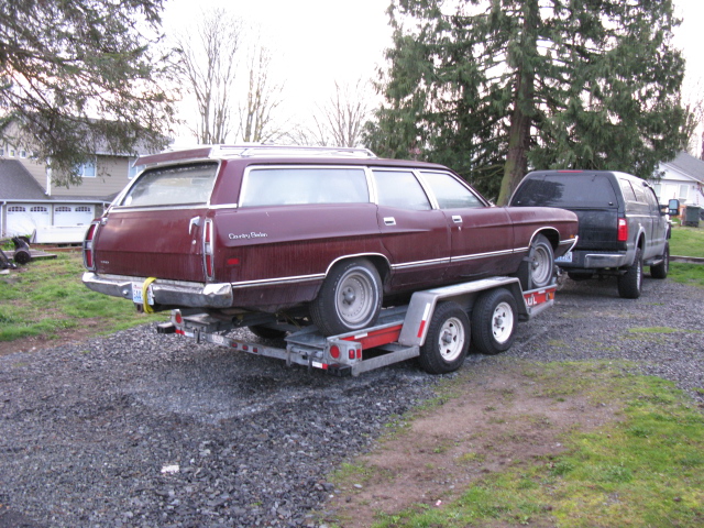 1971 Ford Country Sedan wagon on a trailer, towed by a black SUV