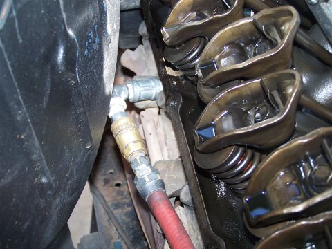 1979 Ford Bronco - Close-up of an engine's valve train, showing rocker arms and springs, with an air hose attached.