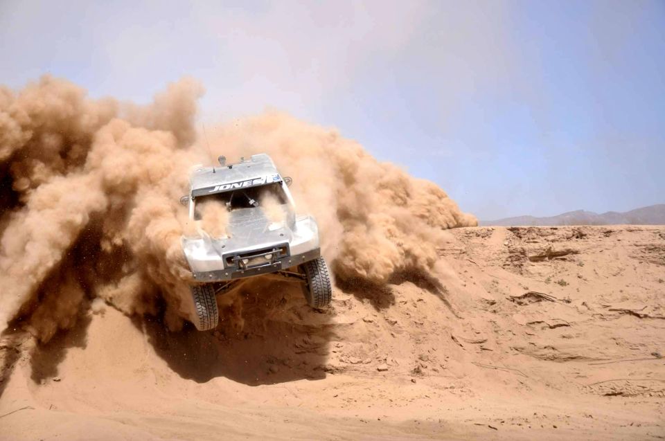 Off-road race truck kicking up dust on a desert track