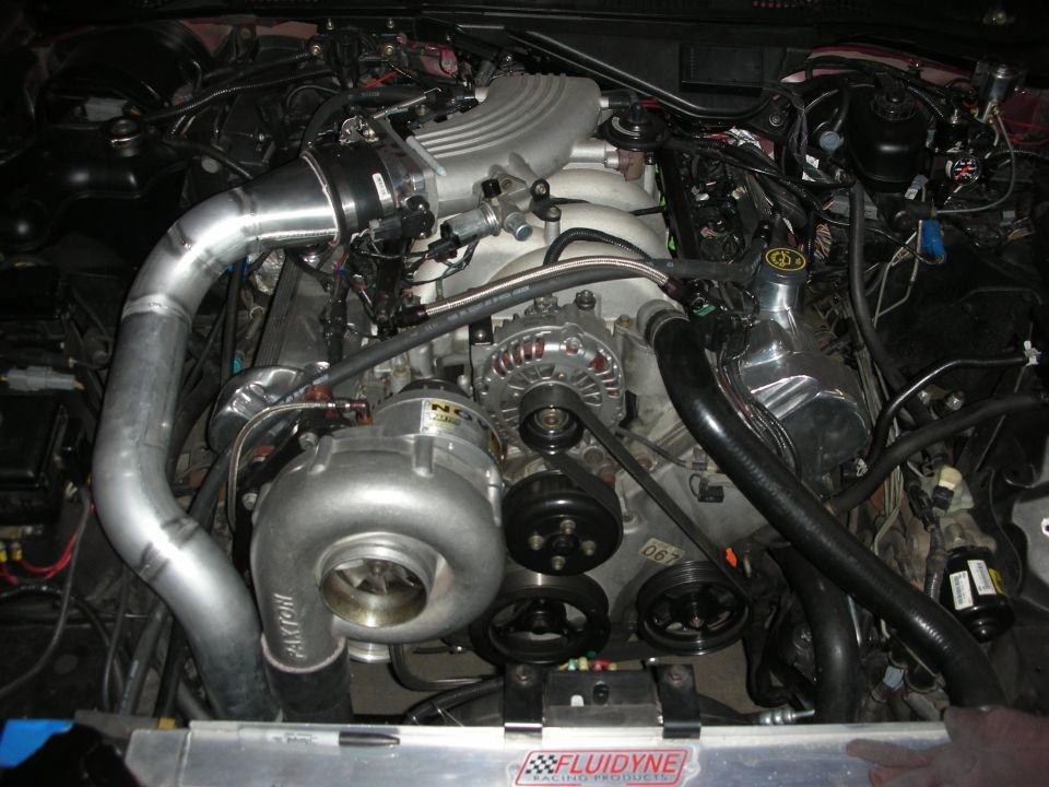 Engine bay with a Paxton supercharger, polished intake manifold, and custom piping. A "Fluidyne Racing Products" sticker is visible