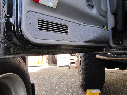 1996 Ford Bronco - The interior door panel of a vehicle shows a vent and the lower section of the door frame.