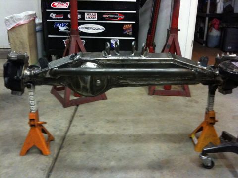 Suzuki Samurai - Front axle assembly supported by jack stands in a workshop setting.