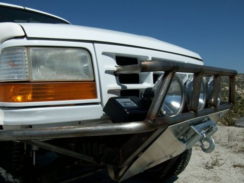 1996 Ford Bronco - Front view of a white Ford truck, likely a 1992-1996 model, equipped with an aftermarket bumper and lighting system.