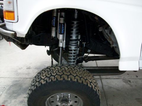 1996 Ford Bronco - The front suspension of a 1996 Ford Bronco features Fox shocks and a large off-road tire.
