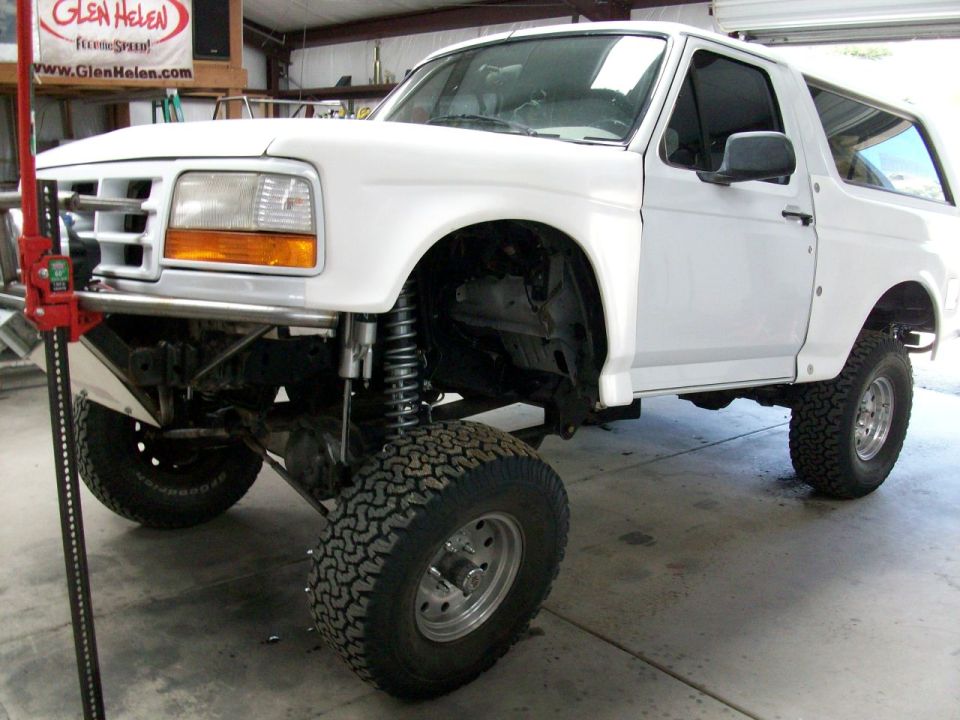 White 1996 Ford Bronco with lifted suspension and off-road tires, jack visible on left