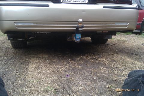 2000 Mercury Grand Marquis - Rear view of a 2000 Mercury Grand Marquis showing the trailer hitch assembly. Another vehicle is partially visible.