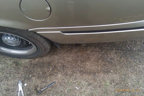 2000 Mercury Grand Marquis - The rear wheel and lower body panel of a gold 2000 Mercury Grand Marquis are visible.