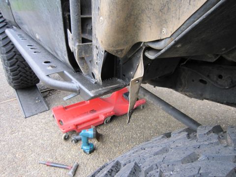 1996 Ford Bronco - Close-up of a vehicle's undercarriage, showing the frame, a side step, and a creeper jack.