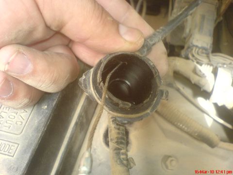 1998 Ford Crown Victoria - A close-up shows the frayed end of a cruise control cable being held by a hand.