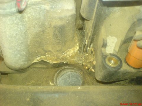 1998 Ford Crown Victoria - Close-up of a corroded engine component, possibly showing signs of a leak.