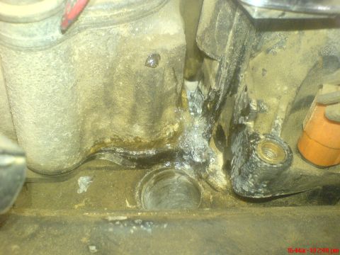 1998 Ford Crown Victoria - Close-up view of corrosion and fluid leakage on an engine component, likely near the thermostat housing.