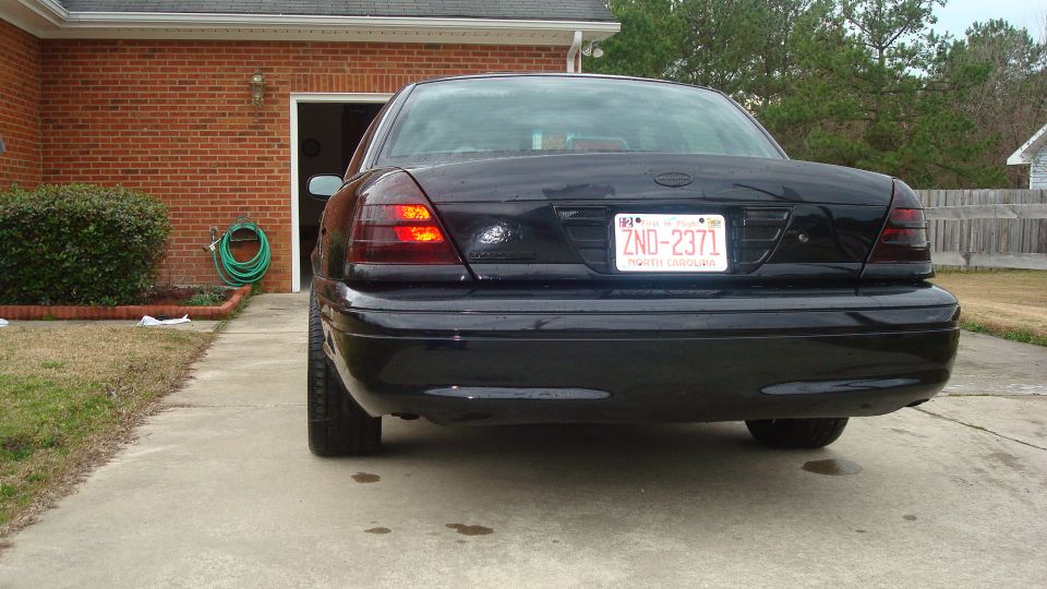 Black 2004 Ford Crown Victoria sedan, rear view, with tinted taillights and a license plate reading ZND-2371