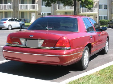2003 Ford Crown Victoria - A red 2003 Ford Crown Victoria is parked in a lot, showing its rear and side profile.