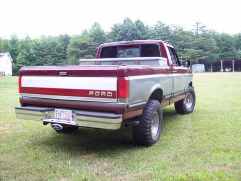 1990 Ford F-150 - Rear view of a lifted Ford F-150 pickup truck parked on a grassy field.