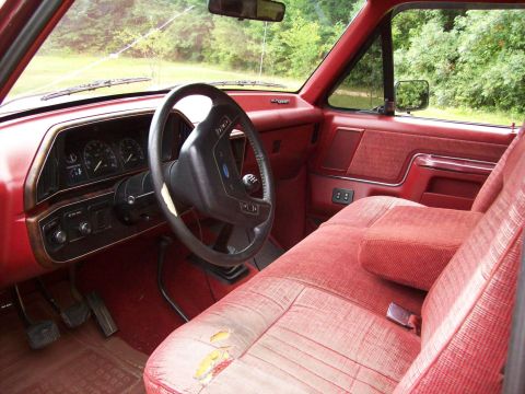1990 Ford F-150 - Interior view of a 1990 Ford F-150, showing the dashboard, steering wheel, and worn red seats.