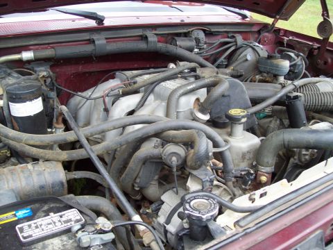 1990 Ford F-150 - A look at the engine compartment, showing various hoses, the battery, and other mechanical parts.