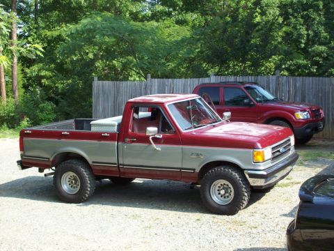 1990 Ford F-150 - This two-tone red and silver 1990 Ford F-150 pickup truck is parked outside with another vehicle behind it.