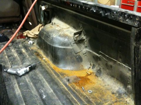 1993 Ford Bronco - The interior of a truck bed displays significant rust and a cordless drill, suggesting repair or restoration work.