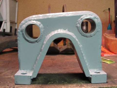 1995 Ford Bronco - A close-up view of a fabricated metal bracket, likely for automotive use, resting on a workbench.