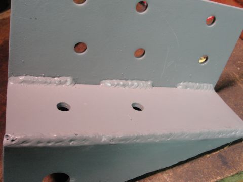1995 Ford Bronco - A close-up view of a gray metal bracket, showing drilled holes and expertly applied welds.