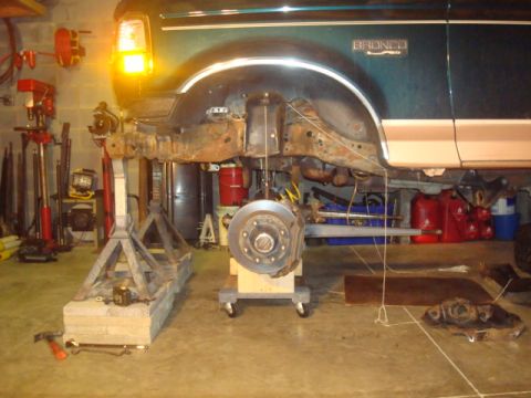 1995 Ford Bronco - The front end of a Ford Bronco is elevated on jack stands, showing the suspension components during a repair.