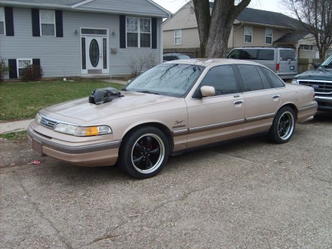 1993 Ford Crown Victoria - A modified sedan with a prominent hood scoop sits parked in front of a suburban house.