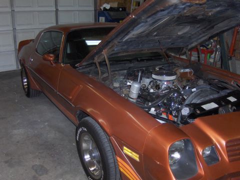 1980 Chevrolet Camaro - This orange coupe has its hood open, revealing the engine compartment and chrome accents.