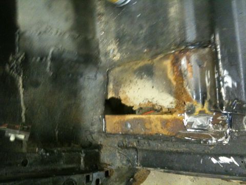 1993 Ford Bronco - The interior floor of a vehicle shows extensive rust damage and structural compromise.