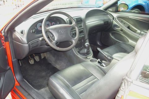 2002 Ford Mustang - The interior of a 2002 Ford Mustang shows black leather seats and a dashboard with a prominent steering wheel.