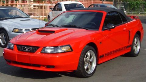 2002 Ford Mustang - Red 2002 Ford Mustang GT convertible with black top, parked outdoors.