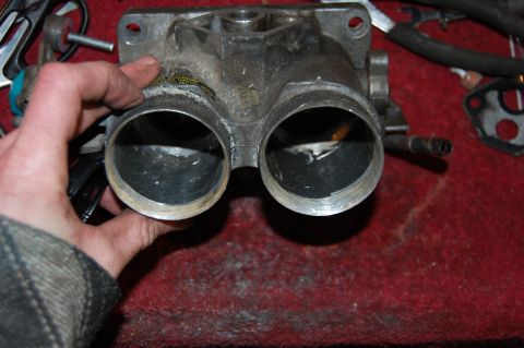 1994 Ford Bronco - Close-up of a throttle body part being held, with other engine components in the background.