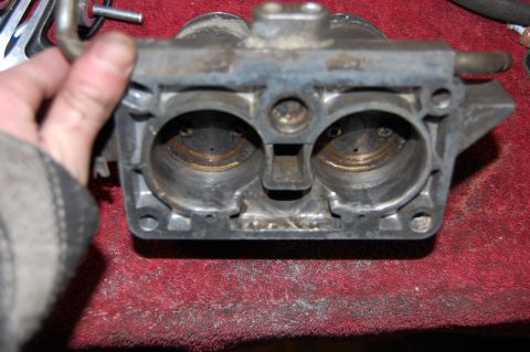 1994 Ford Bronco - Close-up view of a carburetor, likely for a Ford vehicle, held by a gloved hand.