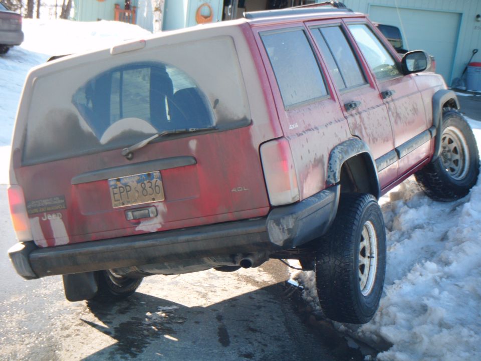 Red Jeep Cherokee parked on snow, rear view. License plate EPP 836
