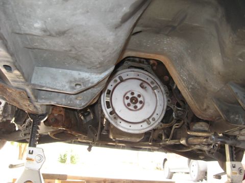 1990 Lincoln Mark VII - The underside of a vehicle is visible, focusing on the transmission and flywheel assembly.