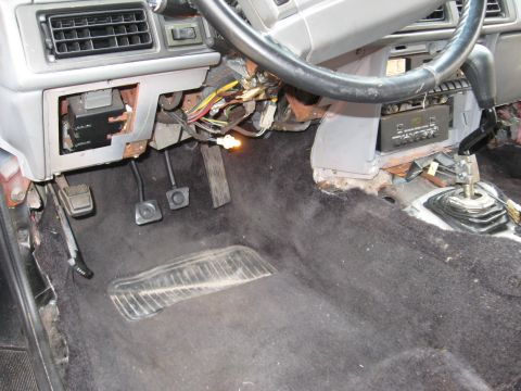 1990 Lincoln Mark VII - Interior view of a car's dashboard and floor, showing exposed wiring and pedals.