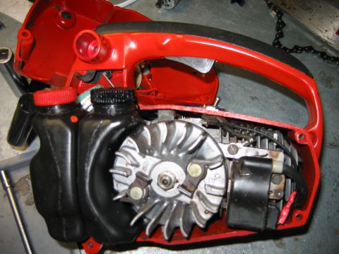 1992 Ford Bronco - Close-up view of a disassembled red chainsaw, showing its internal engine components and fuel reservoirs.