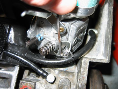 1992 Ford Bronco - A hand adjusts the linkage on a chainsaw's carburetor assembly.