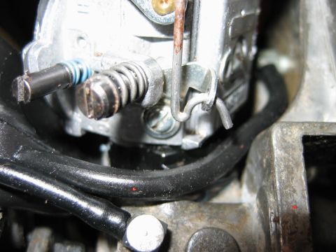 1992 Ford Bronco - Close-up view of a carburetor linkage, showing a spring and screw mechanism.