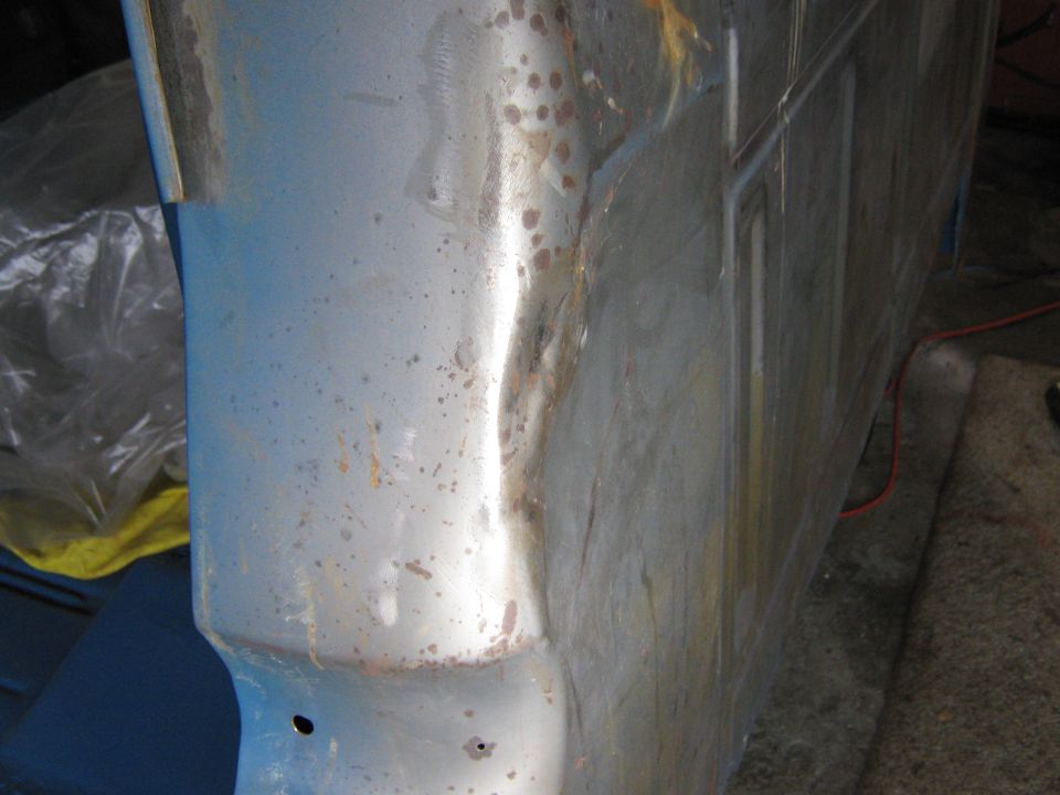 Close-up of a light blue truck fender and door edge with rust spots and some dents