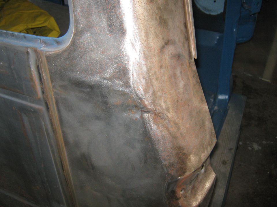 Close-up of a dented and rusted truck body panel being worked on